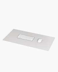 Minimalist Desk Mat in Gray with a keyboard and mouse on a grey background.