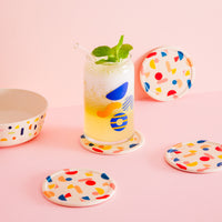 Set of 4 Poketo Bamboo Coasters in Chips with a glass on a pink counter top.