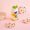 Set of 4 Poketo Bamboo Coasters in Chips with a glass on a pink counter top.