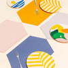Hexagon Placemat in Marigold, gray, cornflower, and pink with bamboo tabletop
