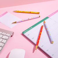 The PK Pattern Twist Pens Set of 4 displayed with other working tools on a pink background. 