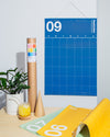 Acrylic poster hanger in large with spectrum wall planner hanging in a workstation setting. 
