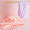 Linen Checkers Tea Towel set in purple and coral on a pink background.